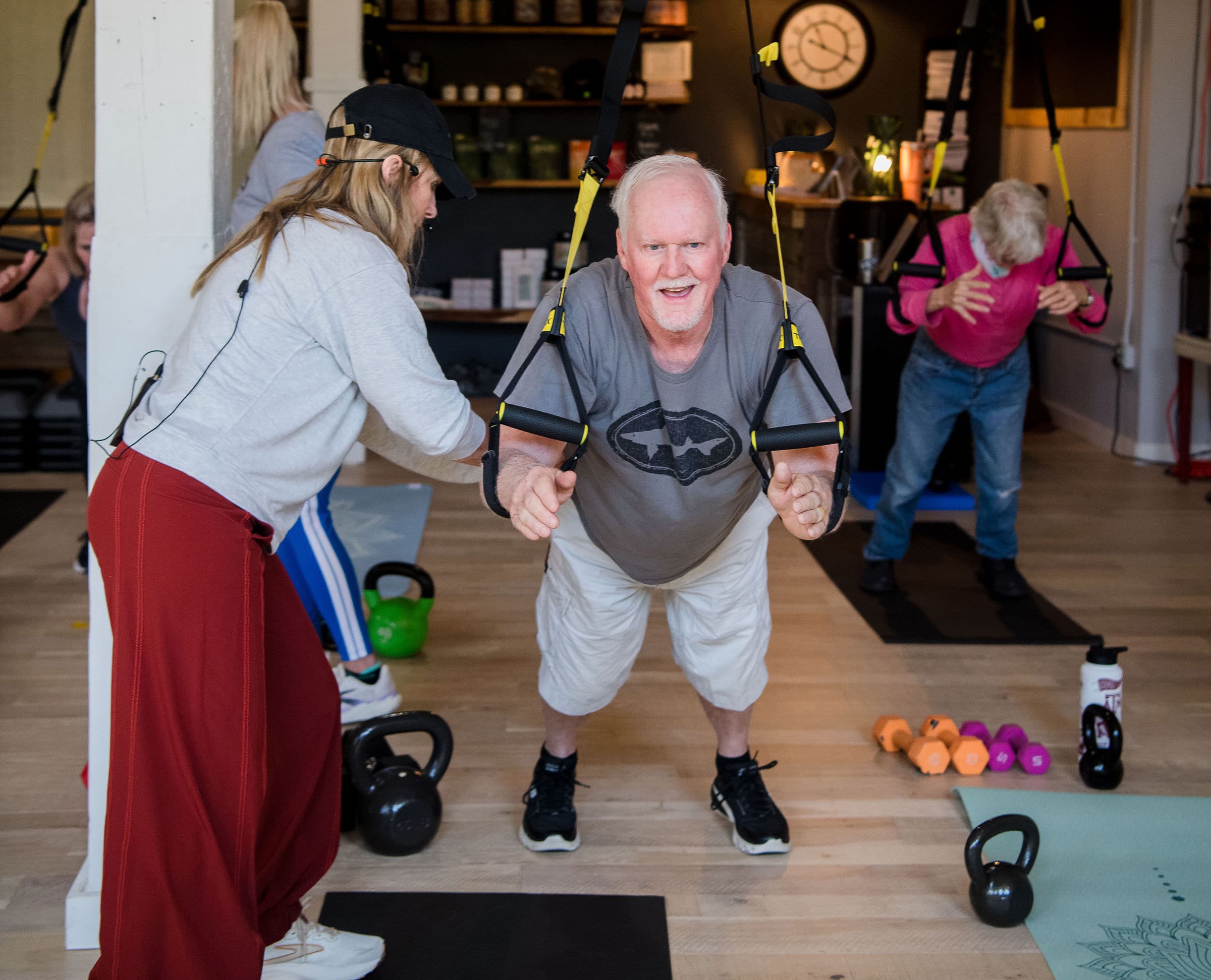 A Get Flexy coach guiding a member through a TRX suspension training exercise in the studio