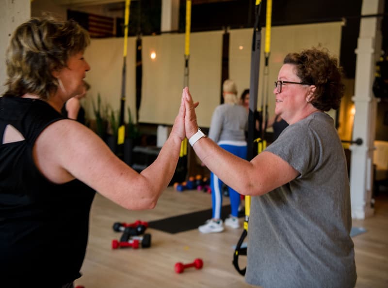 Two Get Flexy members high-fiving each other during a workout in the studio